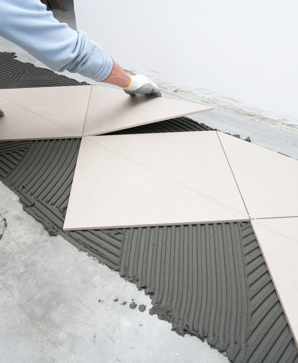 Worker laying triangular tiles on floor